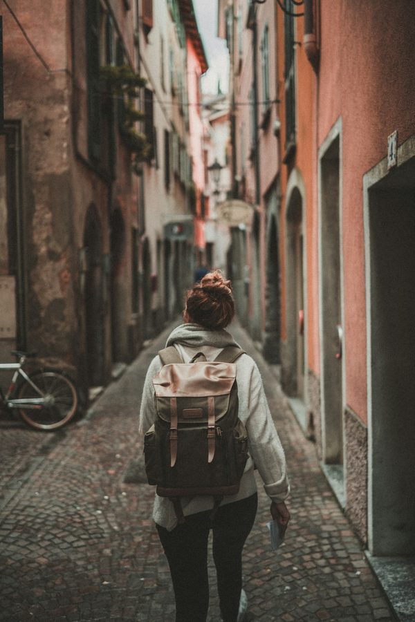 A person with a backpack walking down a narrow alley